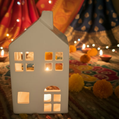 House-shaped candle lantern on a colorful fabric background with lights