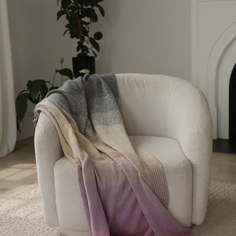 Stack of folded blanket on a chair with a plant in the background