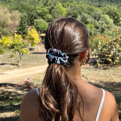 Person with a scrunchie in their hair standing outdoors with mountains in the background