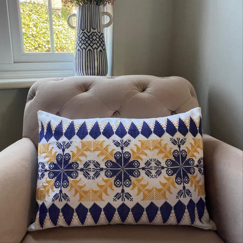 Hand-embroidered pillow with blue and yellow pattern by refugee women in Lebanon