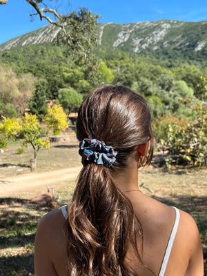 Person with a scrunchie in their hair standing outdoors with mountains in the background