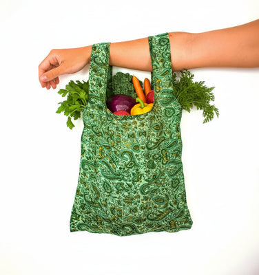 Green patterned reusable bag held by a person on a white background